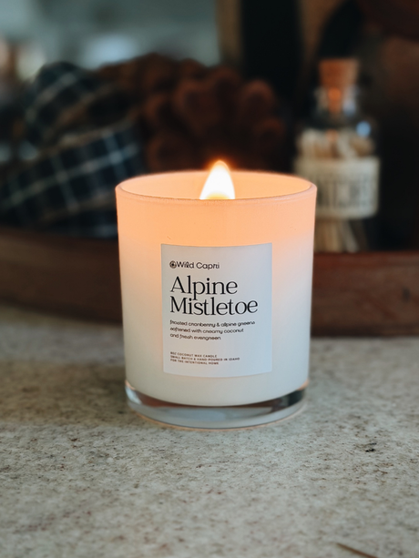 a lit white christmas Alpine Mistletoe frosted cranberry candle on a kitchen counter