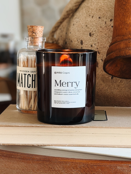 Holiday and Christmas Merry candle by wild Capri lit on a book near a jar of matches in the kitchen 