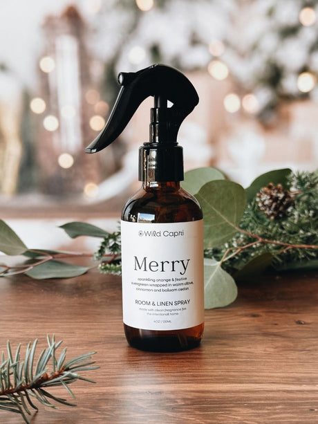 Bottle of Wild Capri 'Merry' room and linen spray with Christmas decorations in the background